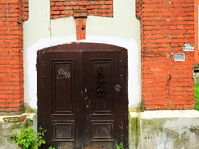 коричневые металлические двустворчатые входные двери в здание из красного кирпича на высоком цоколе
