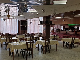 просторный светлый зал столовой СССР с рядами сервированных столиков с белой скатертью и коричневыми стульями вокруг на полу с серой квадратной мраморной плиткой и зеркальным потолком