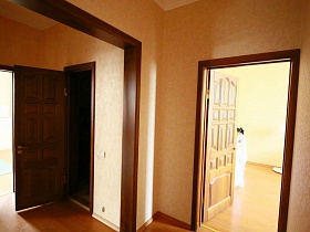 коричневые деревянные двери в разные комнаты с желтыми стенами трехкомнатной квартиры, удобной для переделок и ремонта в жилом доме
