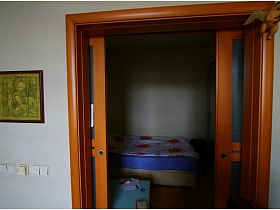 постельное белье с маками на большой кровати в спальне через открытые раздвижные межкомнатные двери в двухкомнатной квартире с видом на Москва-сити