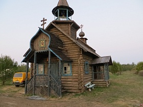 крыльцо со ступенями и перилами небольшой деревянной часовни на открытом участке большой деревни начала 20-го века