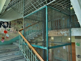 закрытые пролеты лестничной площадки металлической сеткой в подъезде коммунального общежития
