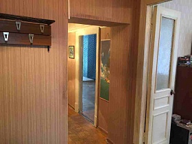 деревянная настенная вешалка с двумя рядами крючков на стене прихожей с сиренево-коричневыми полосатыми обоями квартиры 27