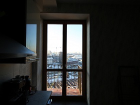 деревянные двери с прозрачным остеклененением из современной кухни на открытый балкон с перилами