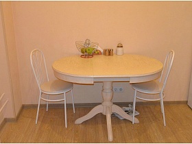 светлый стол на ножке и два белых стула со спинкой в кухне современной квартиры