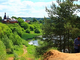 православная церковь в живописном месте в окружении яркой зелени, на берегу петляющего устья  реки