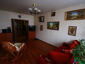 красный мягкий диван и кресло-качалка в леопардовой гостиной обычной трехкомнатной квартиры