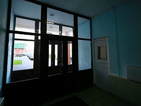 небольшой коридор между входными стеклянными дверьми в вестибюль современного многоэтажного дома в новостройке