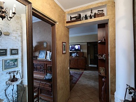 старинная швейная машинка, старые утюги на встроенной полке над входной дверью в гостиную, открытые полочки с фотографиями и статуэтками в углу длинного коридора трехкомнатной квартиры времен СССР