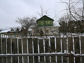 вид на соседние дома по даче из-за досок в деревянном заборе