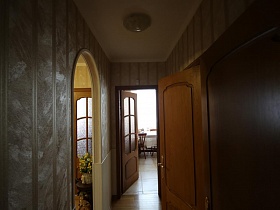 светлые обои в полоску в комнате с многочисленными дверьми в комнаты большой квартиры врача