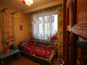 шведская стенка и спортивные снаряды, детский раскладной диван у окна детской