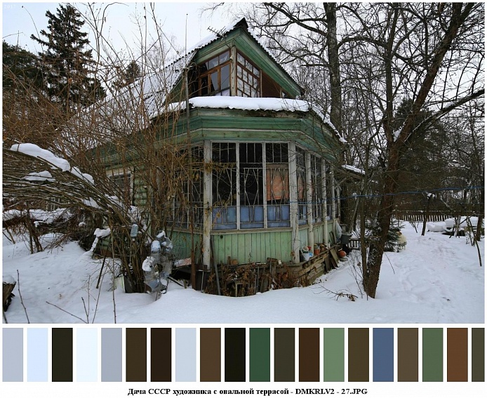 общий вид деревянной советской дачи со старой зеленой краской , многочисленными окнами и шифером на крыше на заснеженном участке с деревьями
