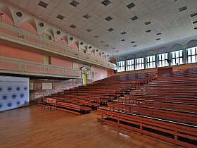 Большая советская аудитория с розовыми стенами и окнами во всю стену позади парт