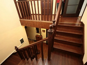 межкомнатные двери на лестничной площадке с перилами и деревянной лестницей между этажами семейного двухэтажного дома в хвойном лесу