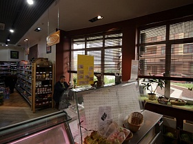 плетенные корзины с готовой кондитерской продукцией на внутреней поверхности витринного холодильника кафе при продуктовом магазине