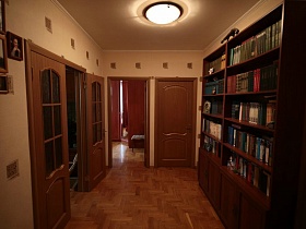 большой книжный шкаф в прихожей песочного цвета в трехкомнатной квартиры