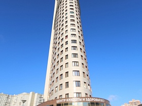 нестандартное полукруглое многоэтажное здание с современной лаконичной минималистической трехкомнатной квартирой в стиле хай-тек под синим небом