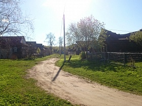 невысокий металлический забор у деревянного дома на окраине старой деревни с многочисленными жилыми домами
