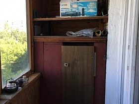 деревянный шкаф с разнообразными вещами на открытых полках застекленной лоджии трехкомнатной квартиры в Бибирево
