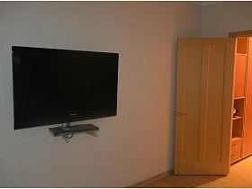 плоский черный телевизор на кремовой стене современной квартиры