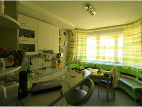 барный столик с серыми высокими стульями в зеленой кухне двухкомнатной квартиры в новострое