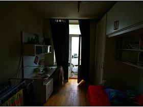 темные шторы на окне с балконной дверью светлой спальной комнаты двухкомнатной квартиры с видом на Москва-сити